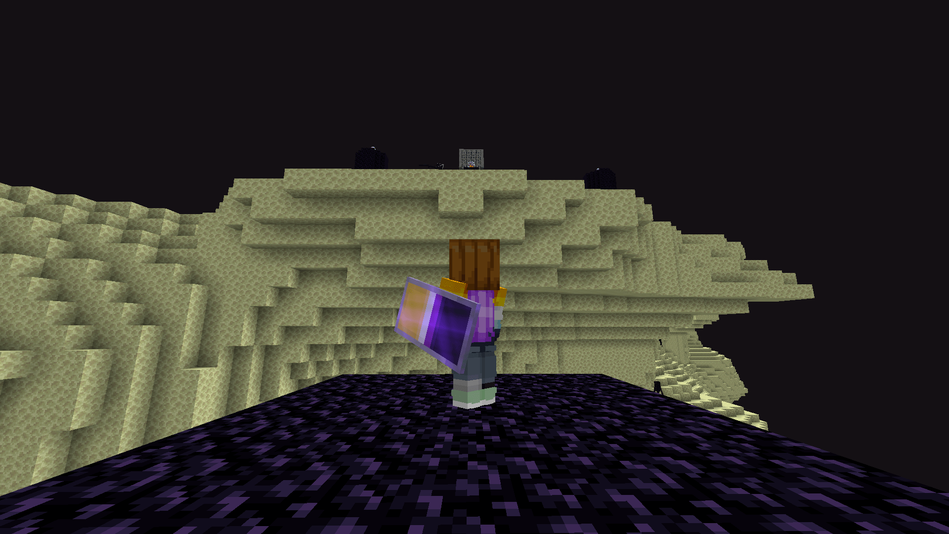 A Minecraft player stands on the End's obsidian spawn platform, wearing a carved pumpkin.