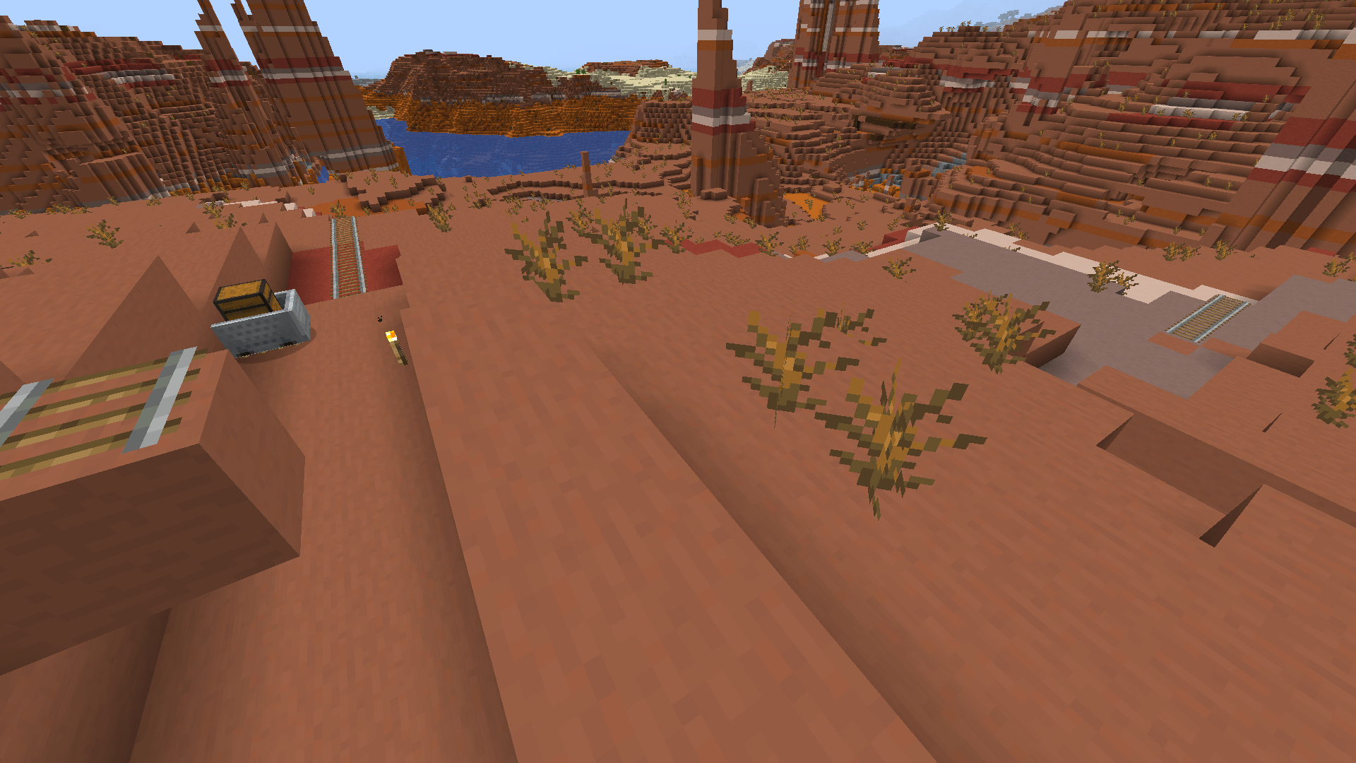 I love it when the Ancient Builders leave their stuff out in the open for me to loot. A section of an abandoned mineshaft on the surface of a badlands biome, including a chest minecart.