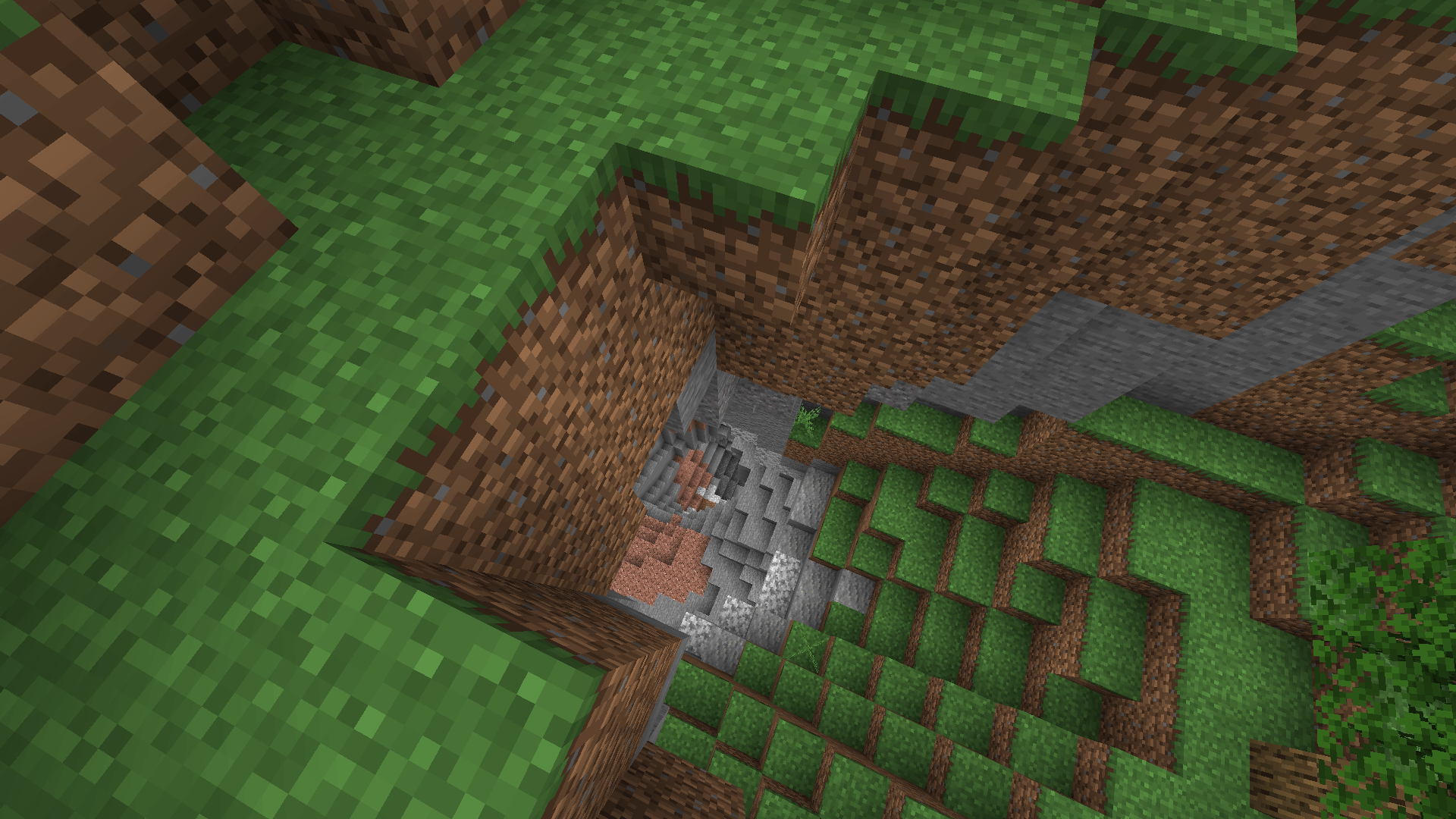 This deathpit has been in my backyard this whole time?! Looking down from a grassy surface into a deep cave, with deepslate visible at the centre of picture.