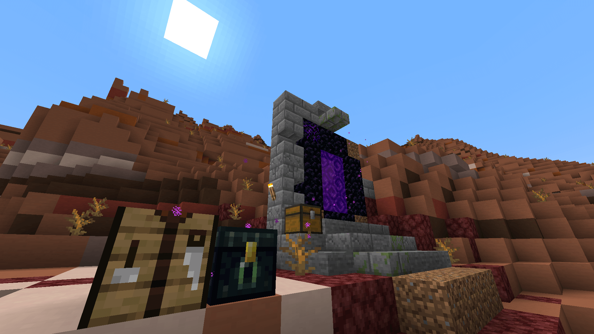 A restored ruined portal in a badlands biome. A crafting table and ender chest lie in the foreground, and the sun is in the upper left of the screen.