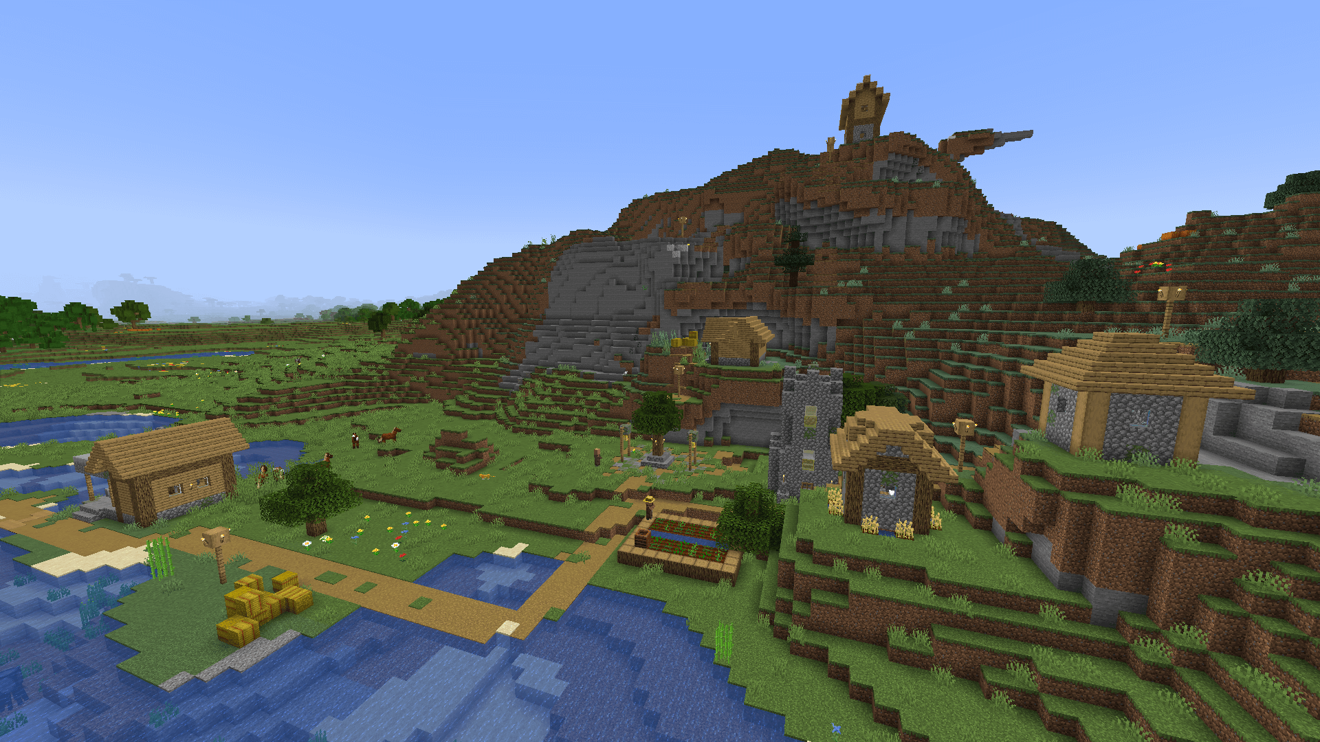 A plains village, mostly on flat ground by the coast but with one house on top of a large hill.