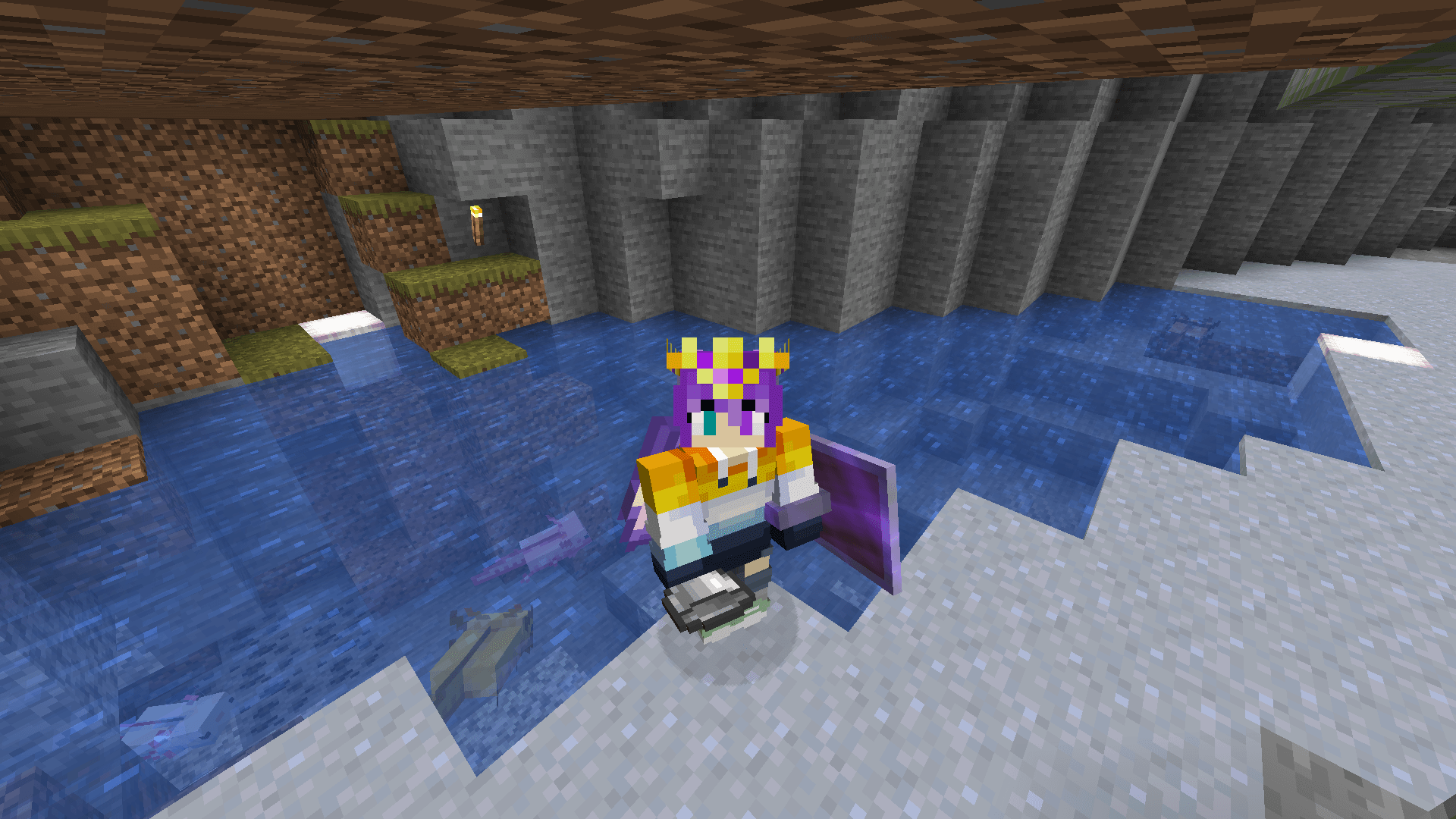 Ela stands on a patch of clay in front of a pond, in which four differently-coloured axolotls swim around.