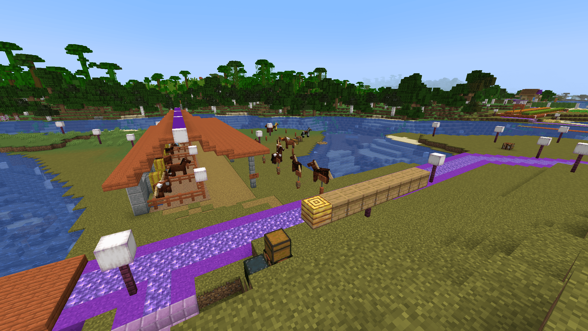 Looking down from a hill at a horse full of stables, and a row of beehives. There are no bees in sight.