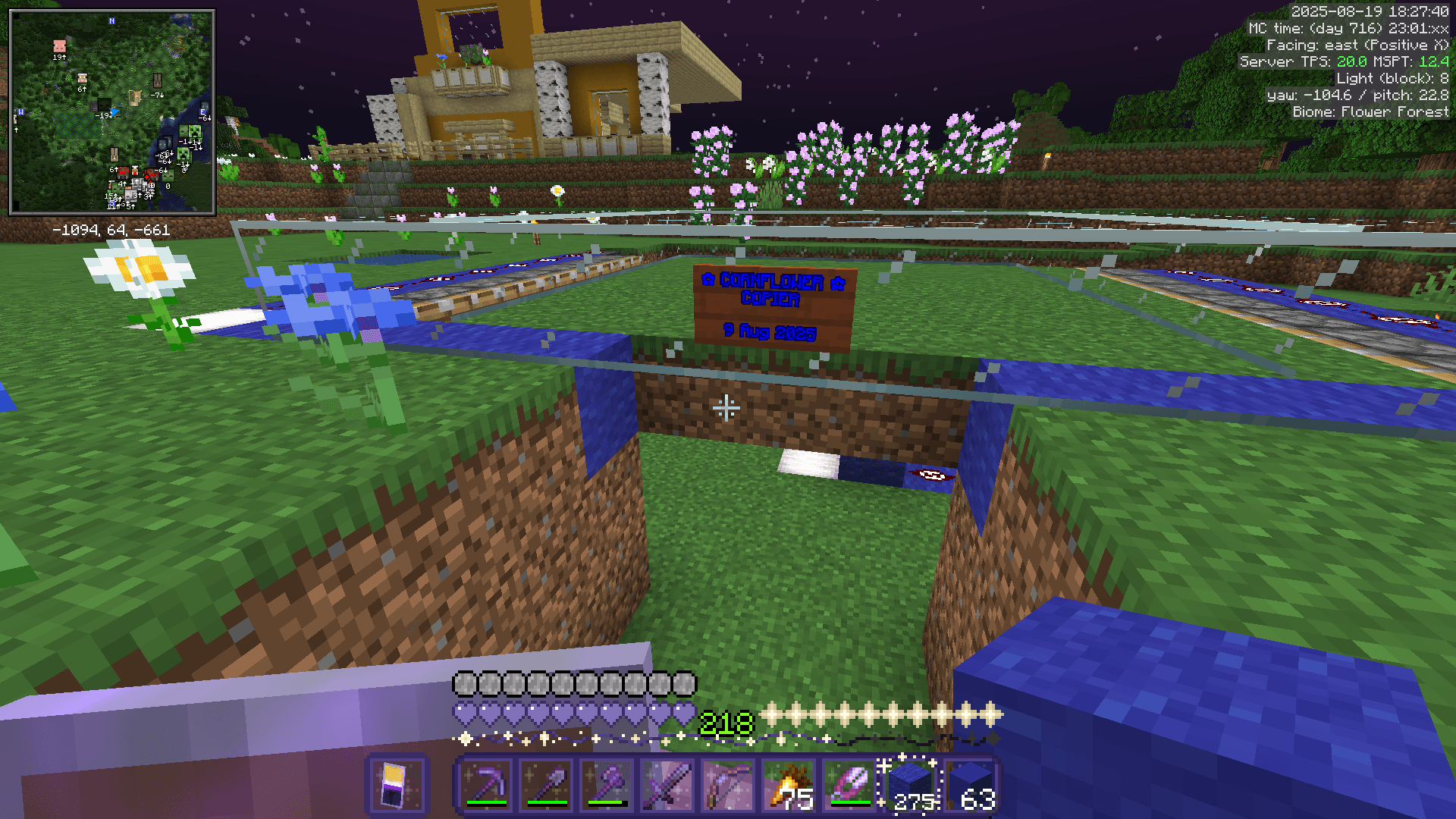 A small grass block platform bordered with glass, pistons, and blue wool. A sign on the front reads: CORNFLOWER COPIER.