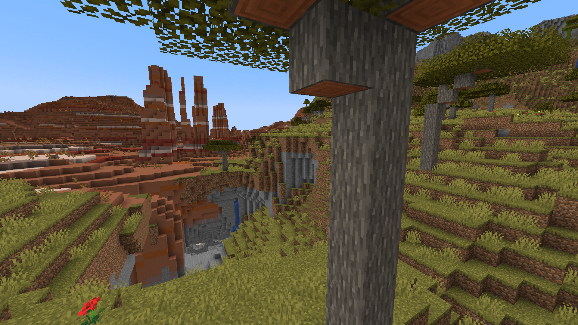 What a lovely scenic spot. Hey, I wonder where that water leads to? A cave entrance with acacia trees in the foreground and badlands in the background.
